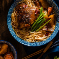 These spicy chicken noodles feature a super rich broth with juicy chicken. Learn to use the steam braising skill to cook a very flavorful chicken in much less time! | omnivorescookbook.com