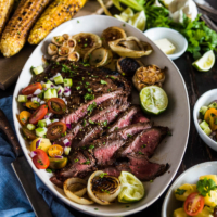 This recipe shares the secrets to creating the tenderest marinated flank steak that is bursting with flavor; included are salad and side dish ideas for an inexpensive dinner party.