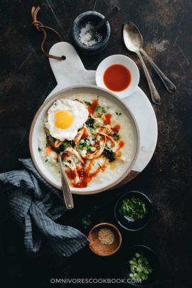 Instant Pot congee with chicken and spinach topped with egg served in a bowl with sauce and toppings on the side