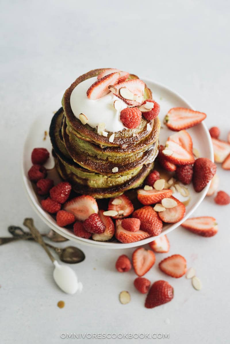 One stack of matcha pancakes with strawberry topping, whipped cream, and syrup