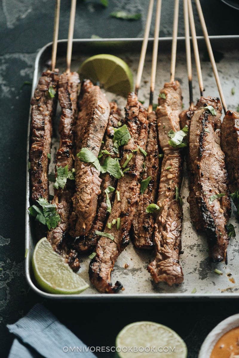 Beef satay served with peanut sauce and cilantro close up