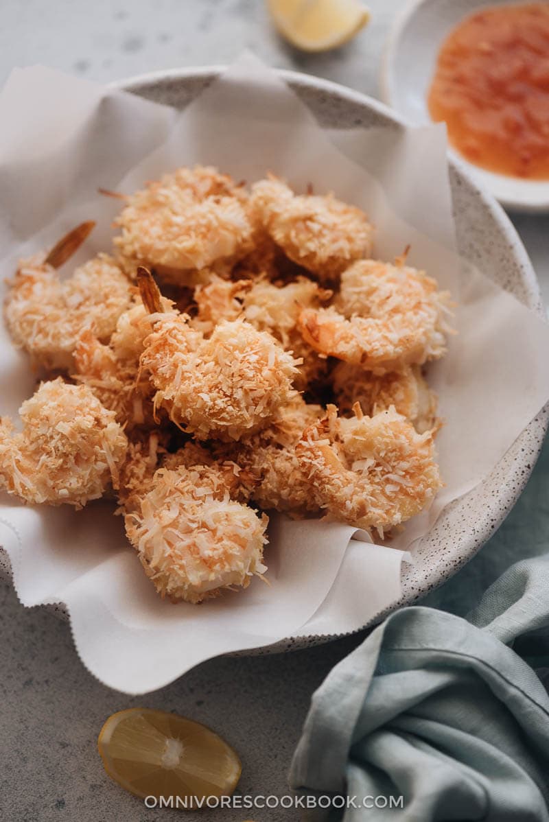 A bowl of crispy coconut shrimp served with sweet chili sauce closeup