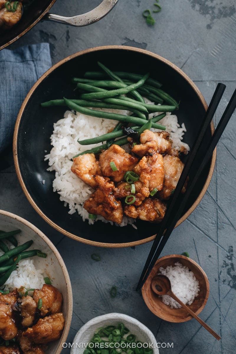 Homemade crispy Chinese honey chicken served in bowls with rice and green beans