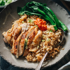 Carved chicken served on rice with Chinese broccoli