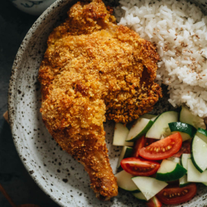 Crispy baked chicken leg served with rice and salad