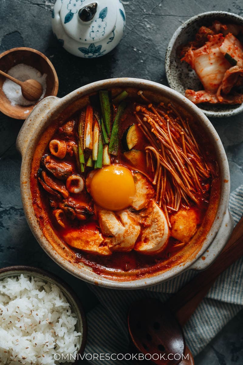 An overhead shot of Korean soft tofu stew. The stew is topped with a raw egg yolk. 