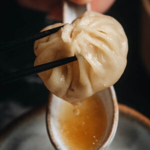 Homemade soup dumplings dripping soup into a spoon