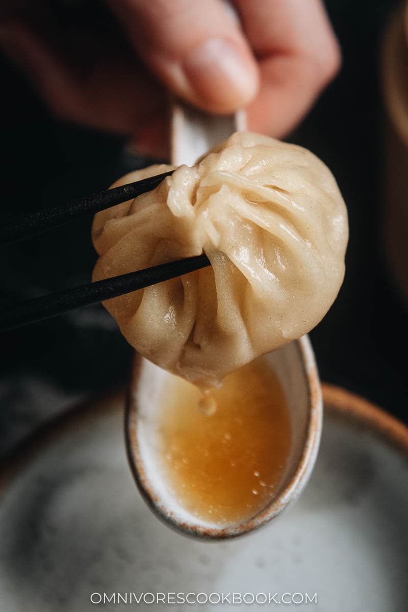 Homemade soup dumplings dripping soup into a spoon