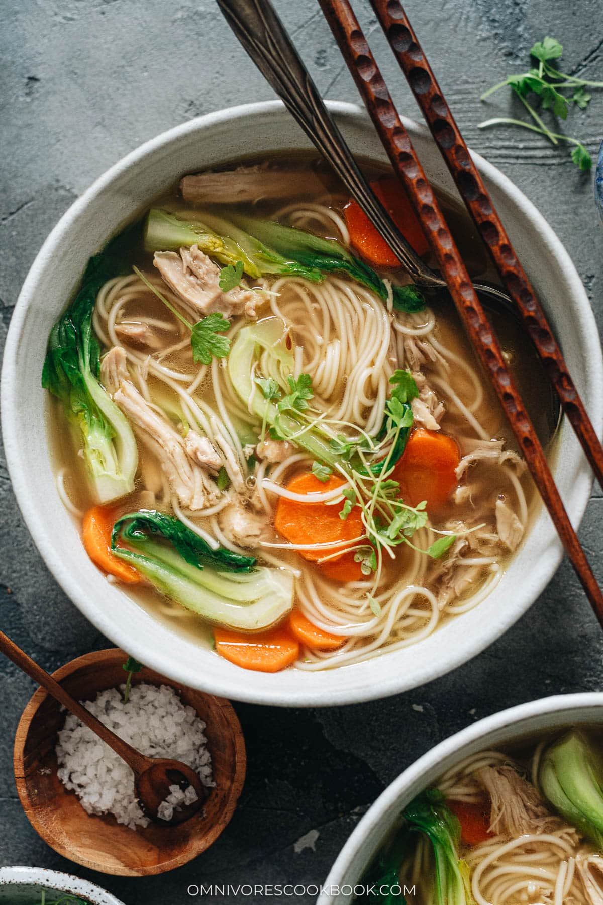 Bowl of noodle soup with shredded chicken, carrot and baby bok choy