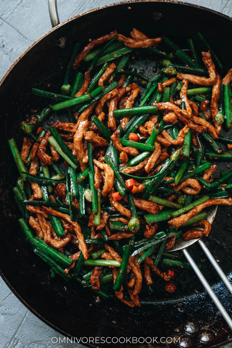 A skillet full of stir fried pork with garlic chives