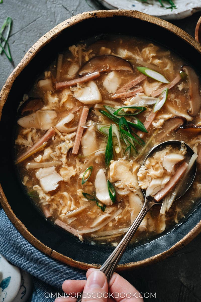 A bowl of soup with mushroom, ham, egg, and fish