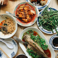 A Sichuan Chinese dinner spread with whole fish, mapo tofu, green beans, and eggplant