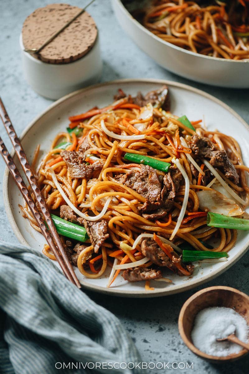 A plate of stir-fried Asian style noodles with chopsticks