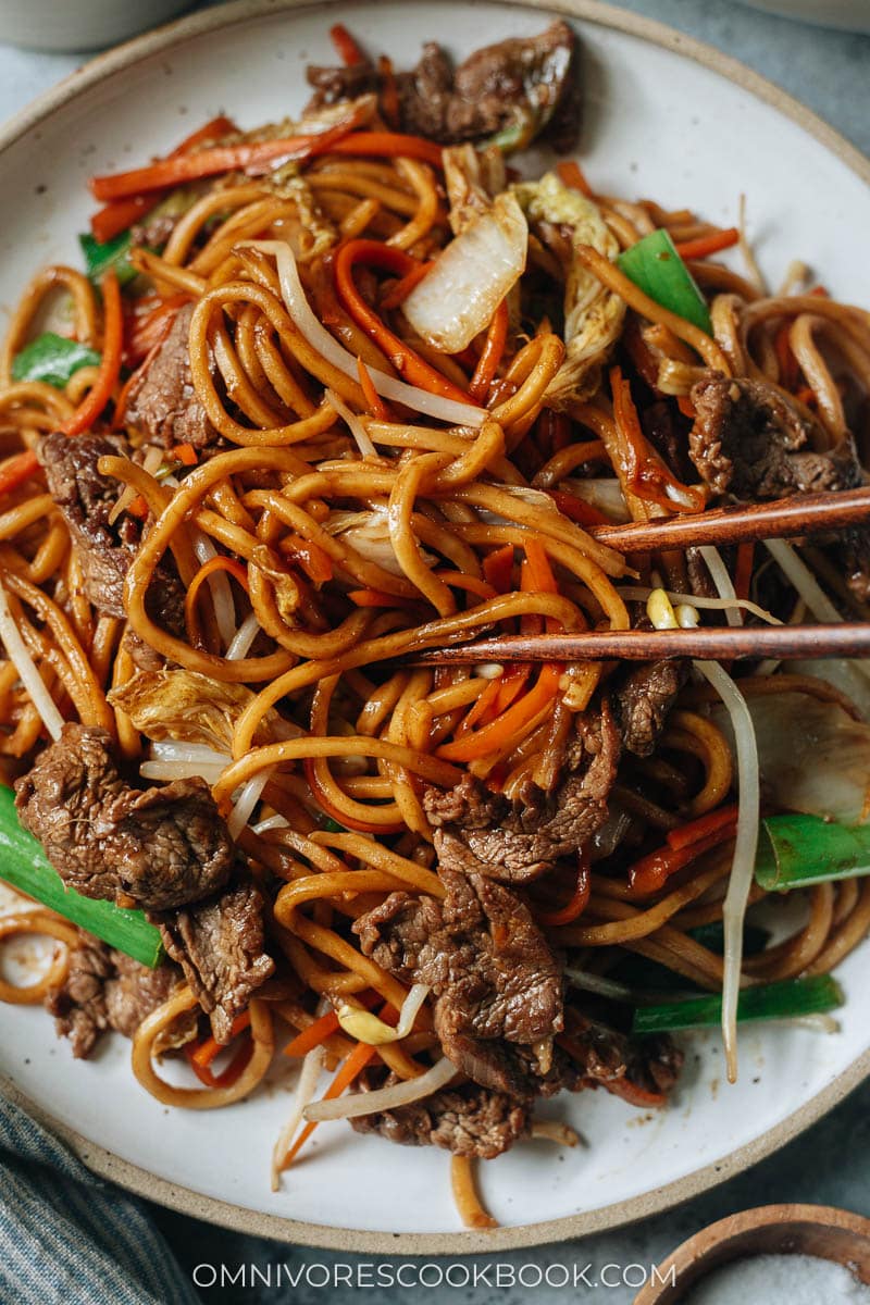 Closeup of chopsticks grabbing a bite of beef lo mein