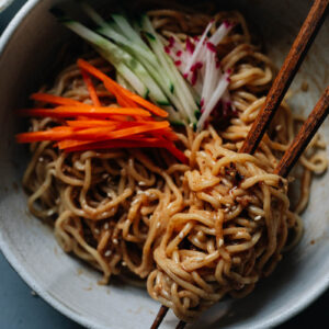 Chinese noodles in a bowl with sesame sauce and vegetables
