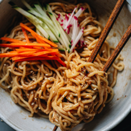 Chinese noodles in a bowl with sesame sauce and vegetables