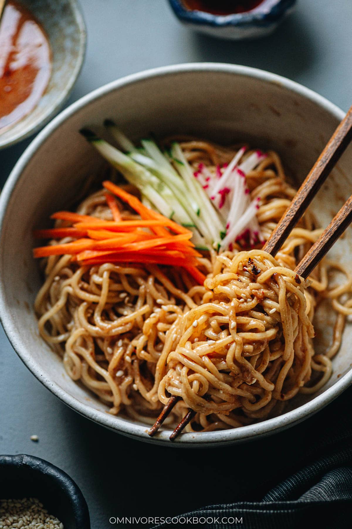 Closeup of nutty Chinese noodles in a bowl with chopsticks