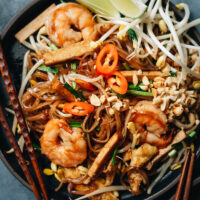 Easy shrimp fried noodles with egg and tofu, peanuts, chili pepper, and lime