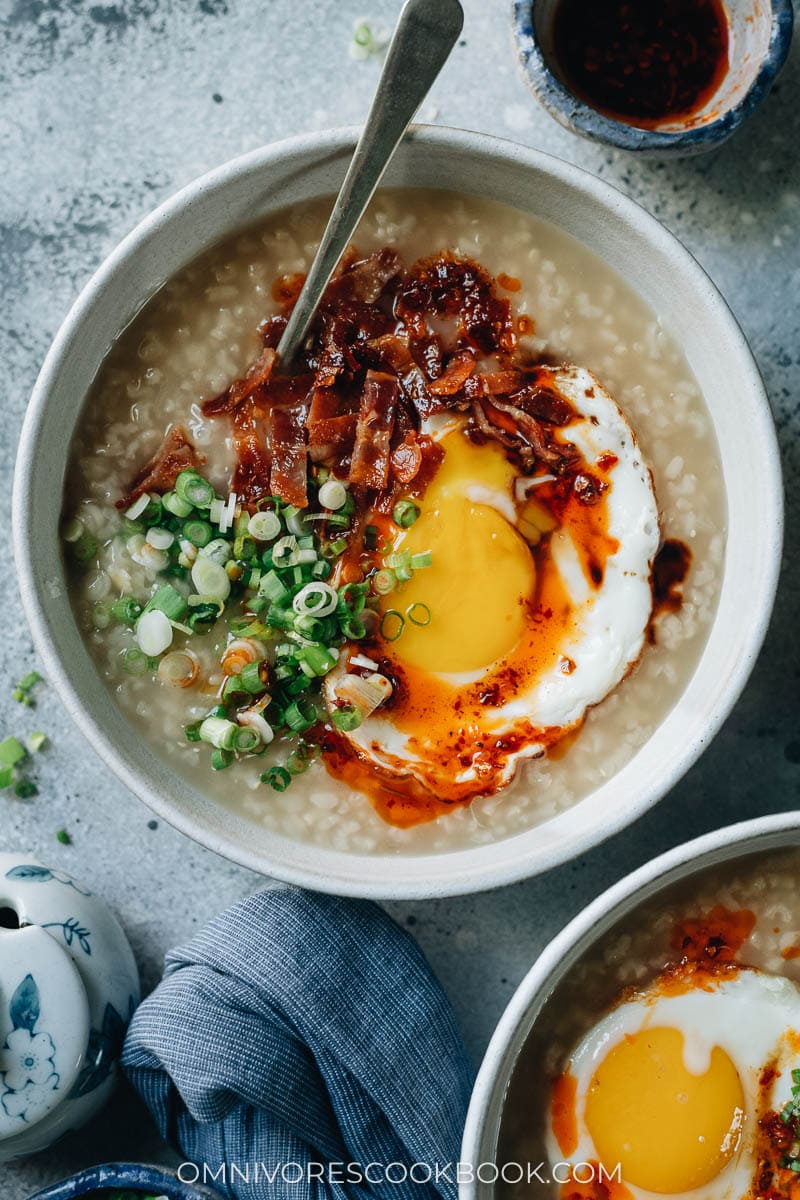 Asian porridge topped with bacon and sunny side up egg and scallion