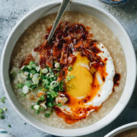 A super simple Instant Pot breakfast congee made with chicken broth and seasoned with ginger and green onion. It’s cooked until gooey, then finished up with crispy bacon, a sunny side up egg, and chili oil. It takes no time to put together and is comforting at any time of the day. {Gluten-free Adaptable}