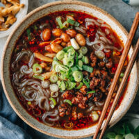 Sharing a signature Sichuan dish Suan La Fen - a bowl of tender springy potato noodles smothered in a rich savory hot and sour soup topped with crispy pork and peanuts. It’s quite easy to put together and addictive to eat! {Vegetarian / Vegan Adaptable, Gluten-Free Adaptable}
