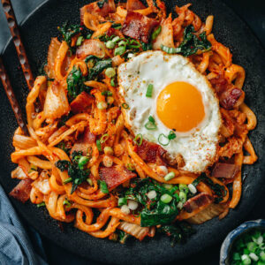 Korean fried noodles with kimchi, bacon and kale