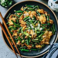 Crisp stir fried garlic scapes with fluffy eggs in a rich, fragrant brown sauce with a hint of sweetness. This recipe shares a super quick and easy way to consume a large amount of garlic scapes. Vegetarian, Gluten-Free Adaptable