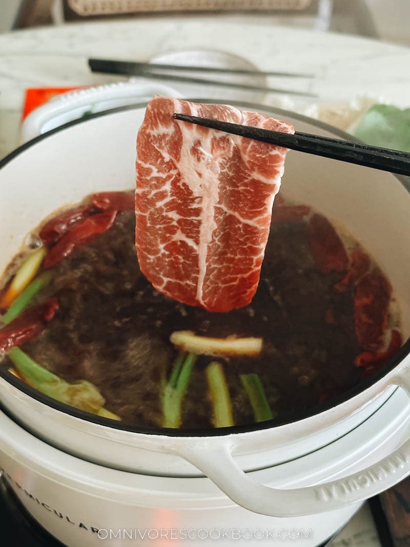 Dipping meat into hot pot broth