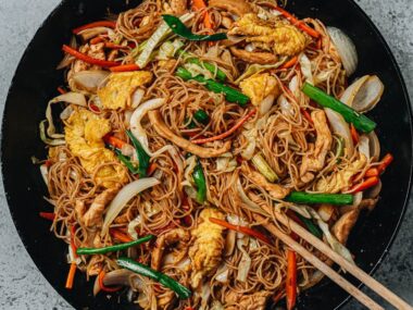 Stir fried rice noodles with chicken, eggs and vegetables in a pan