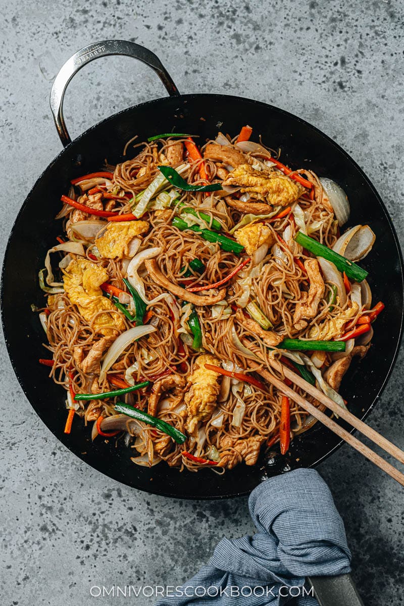 Stir fried rice noodles with chicken, eggs and vegetables in a pan