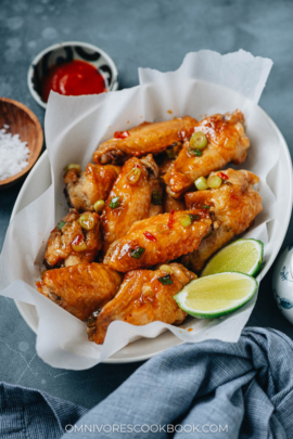 Crispy air fryer wings coated with sauce and served with lime and hot sauce