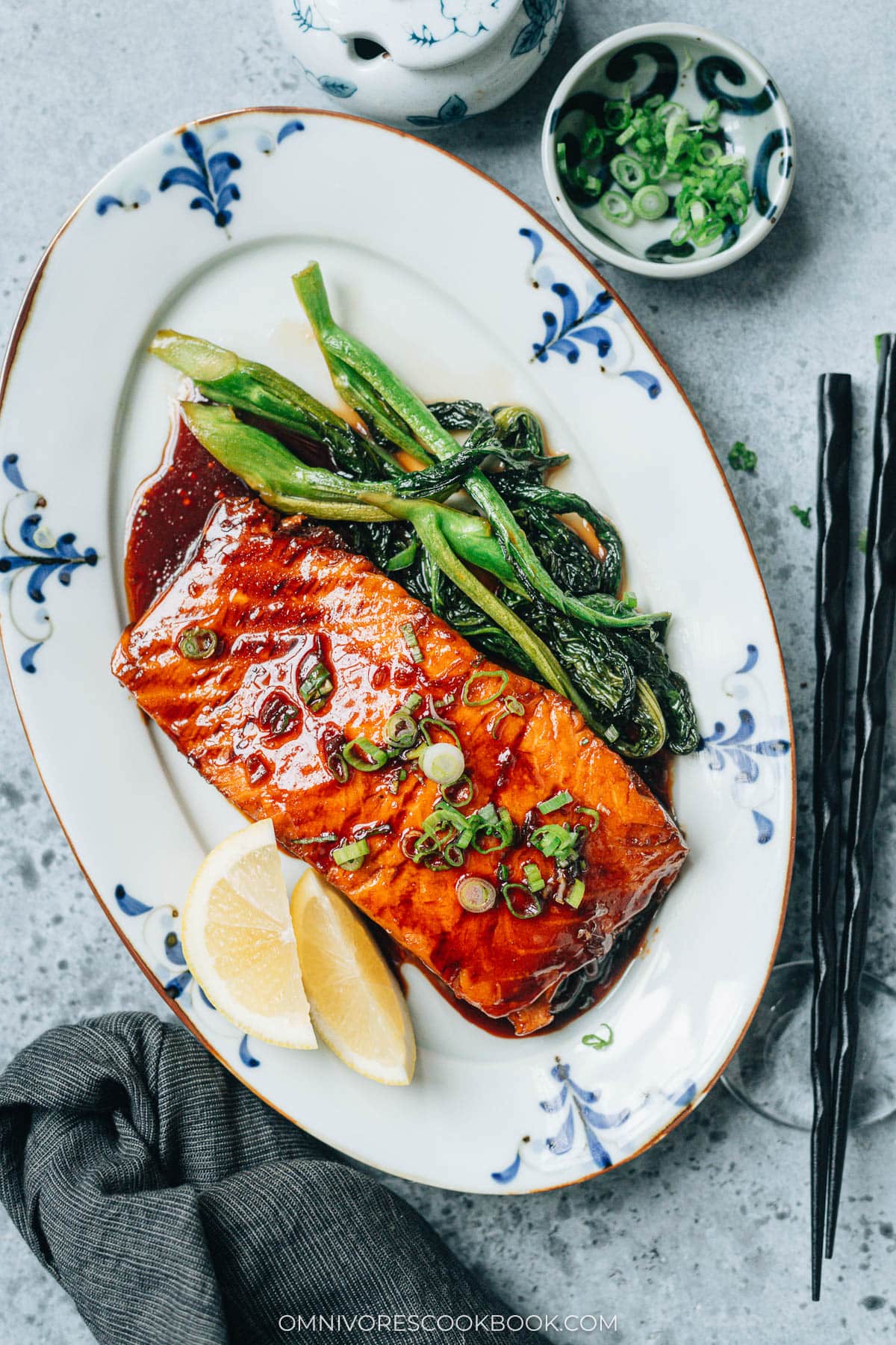 Serving honey glazed salmon with lemon and greens in a plate