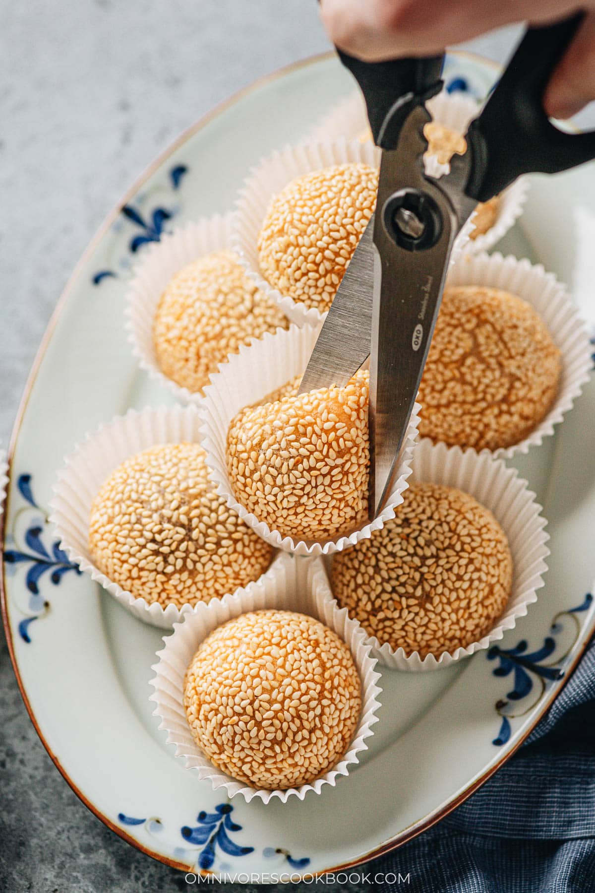 Using a pair of scissors to cut open sesame balls