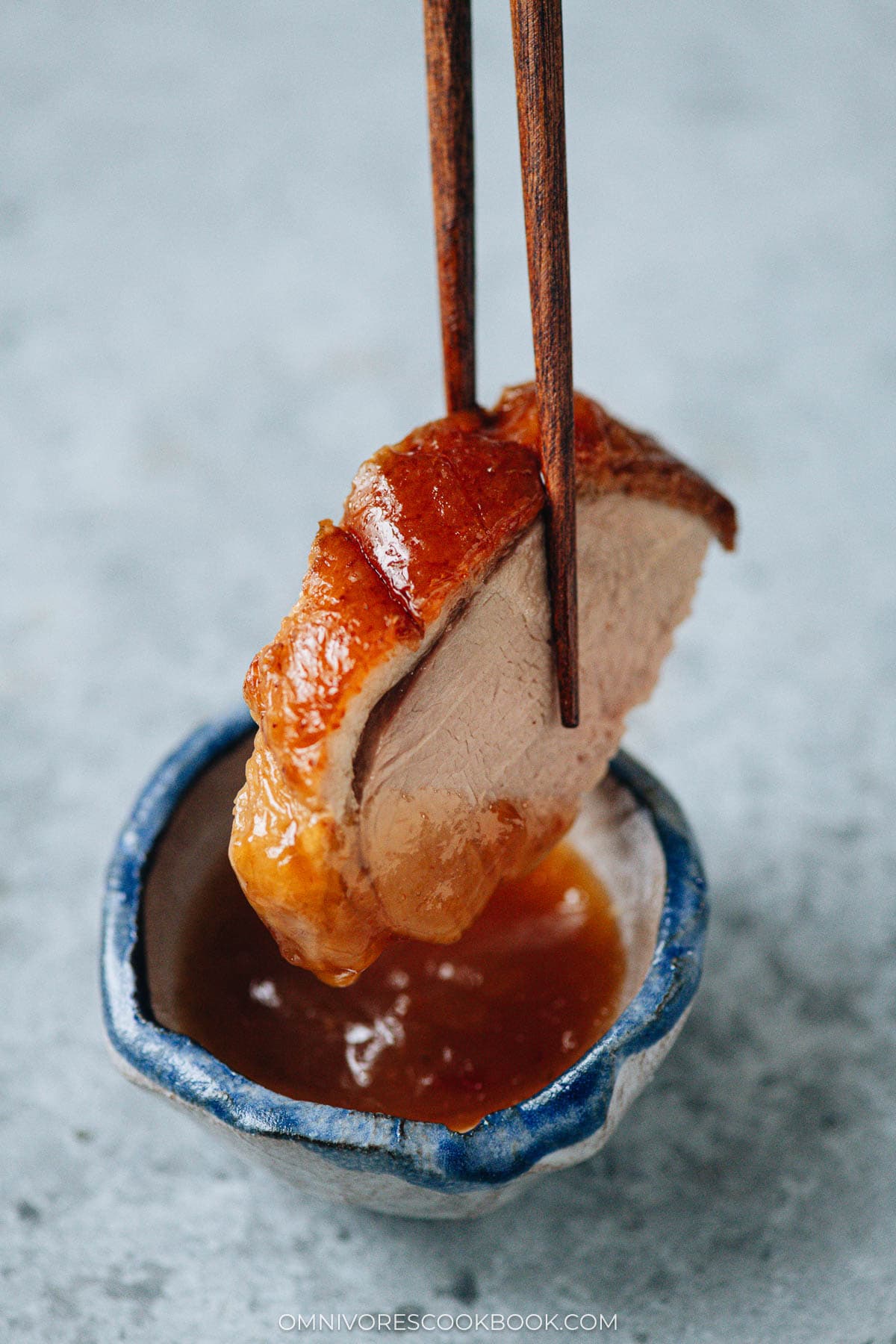 Dipping a slice of Chinese roast duck in plum sauce