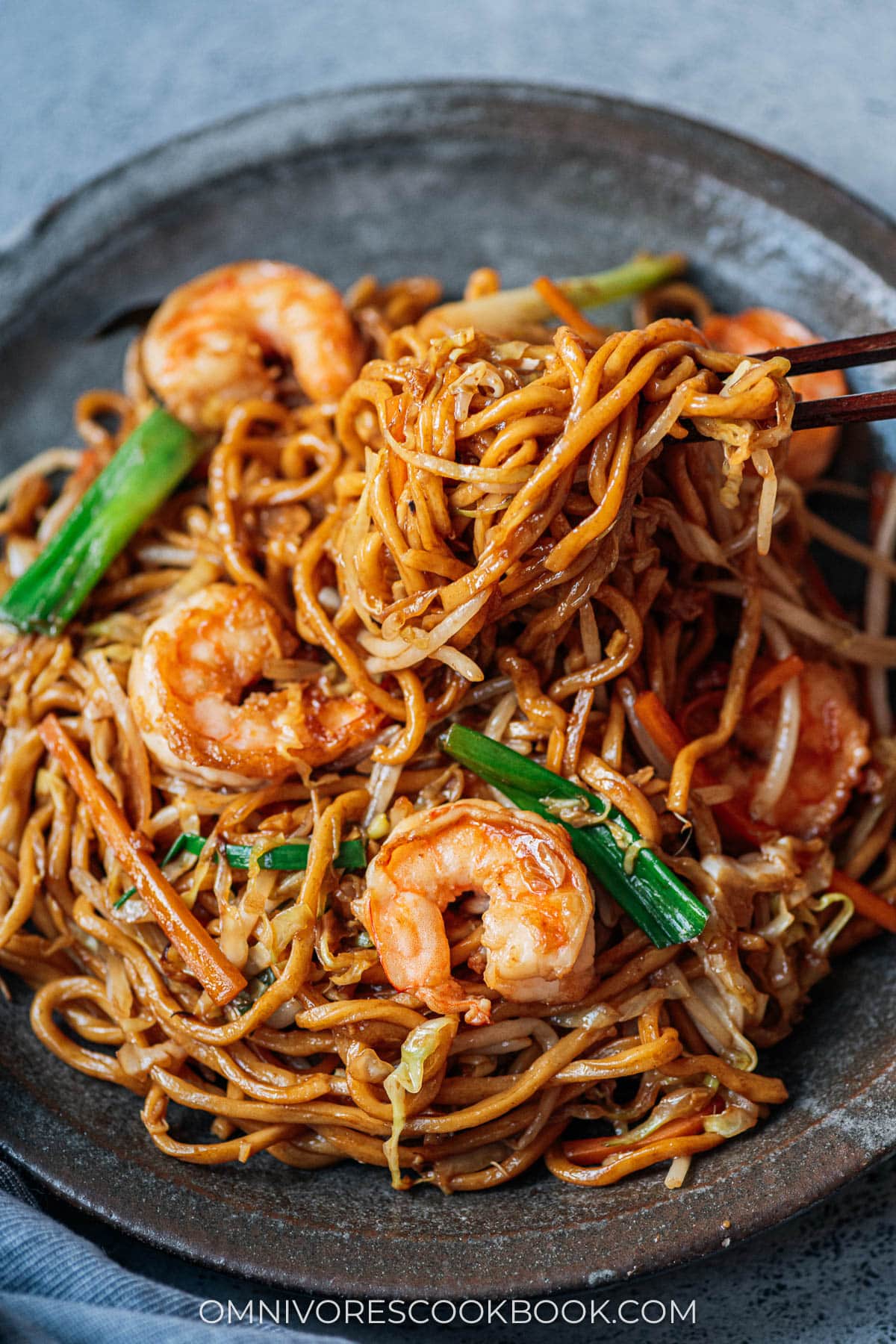 Using a pair of chopsticks to serve shrimp lo mein