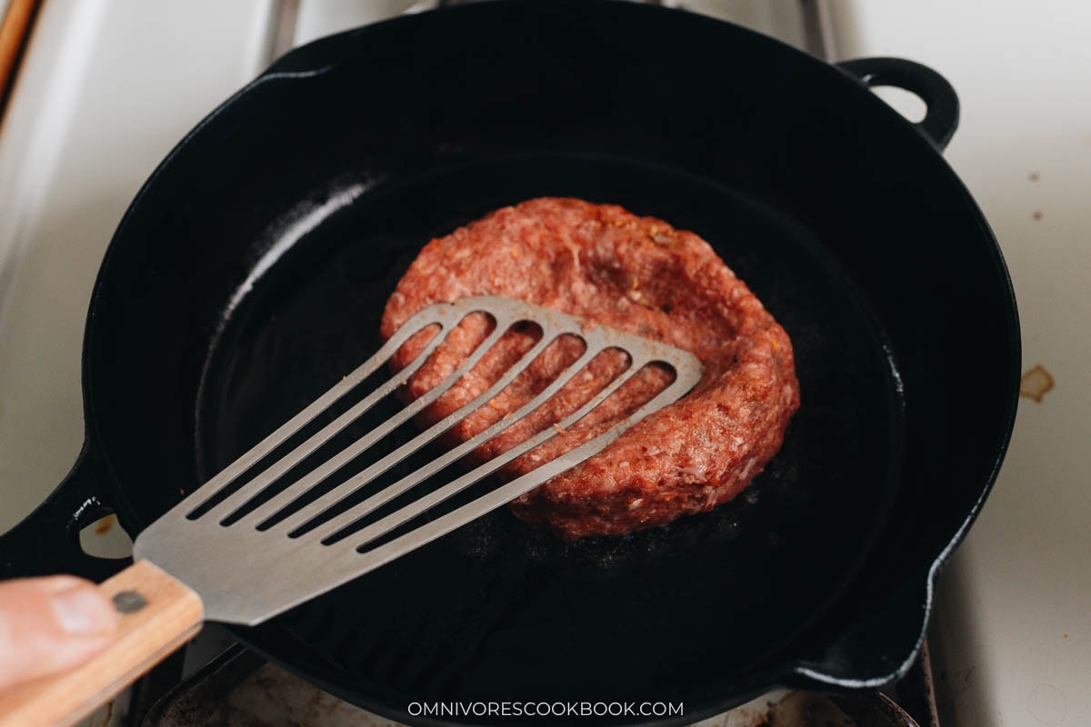 Grill lamb burger patty on a cast iron skillet