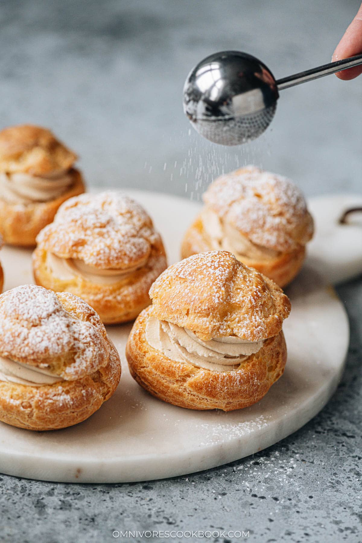 Dust powdered sugar over choux pastry