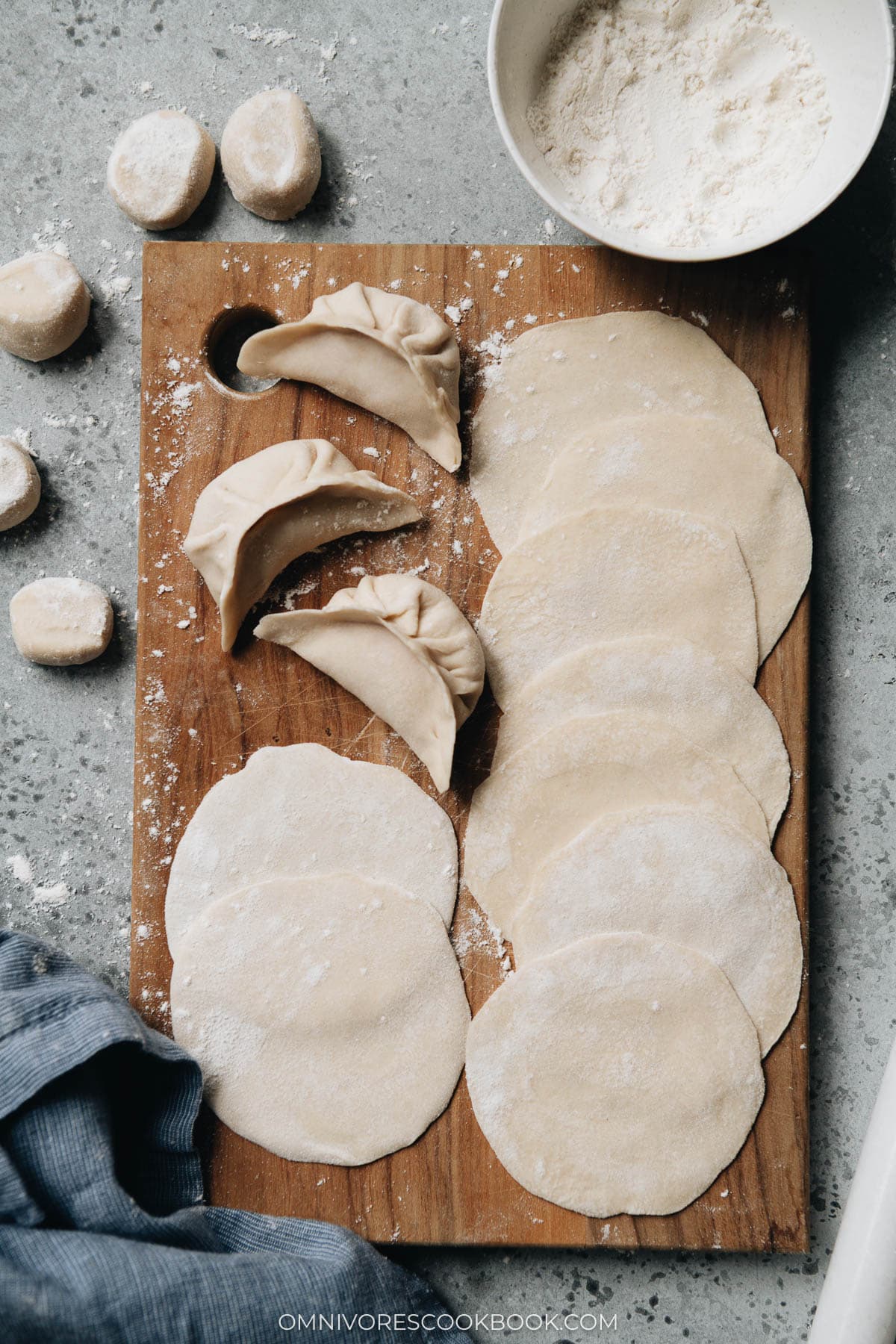 Homemade dumpling wrappers and uncooked dumplings on a cutting board