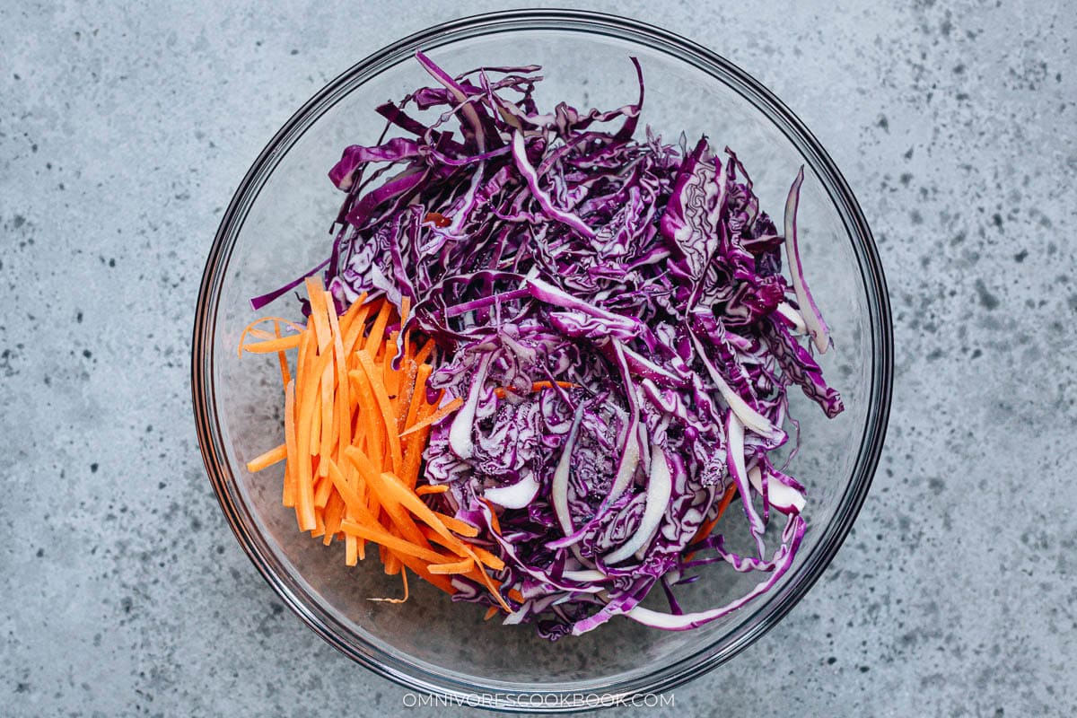 Shredded purple cabbage and carrots sprinkled with salt before mixing.