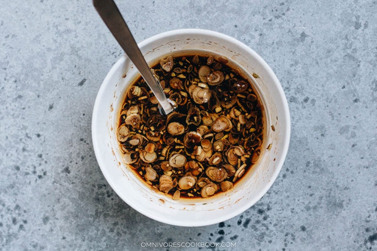 Soy-vinegar dressing with chopped garlic and green onion in a small bowl.