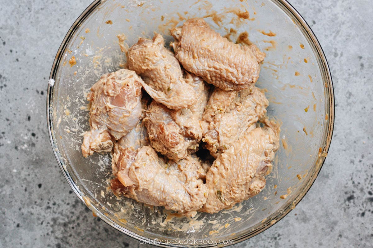 Wings coated with flour, forming a sticky batter that clings to the surface before adding cornstarch.