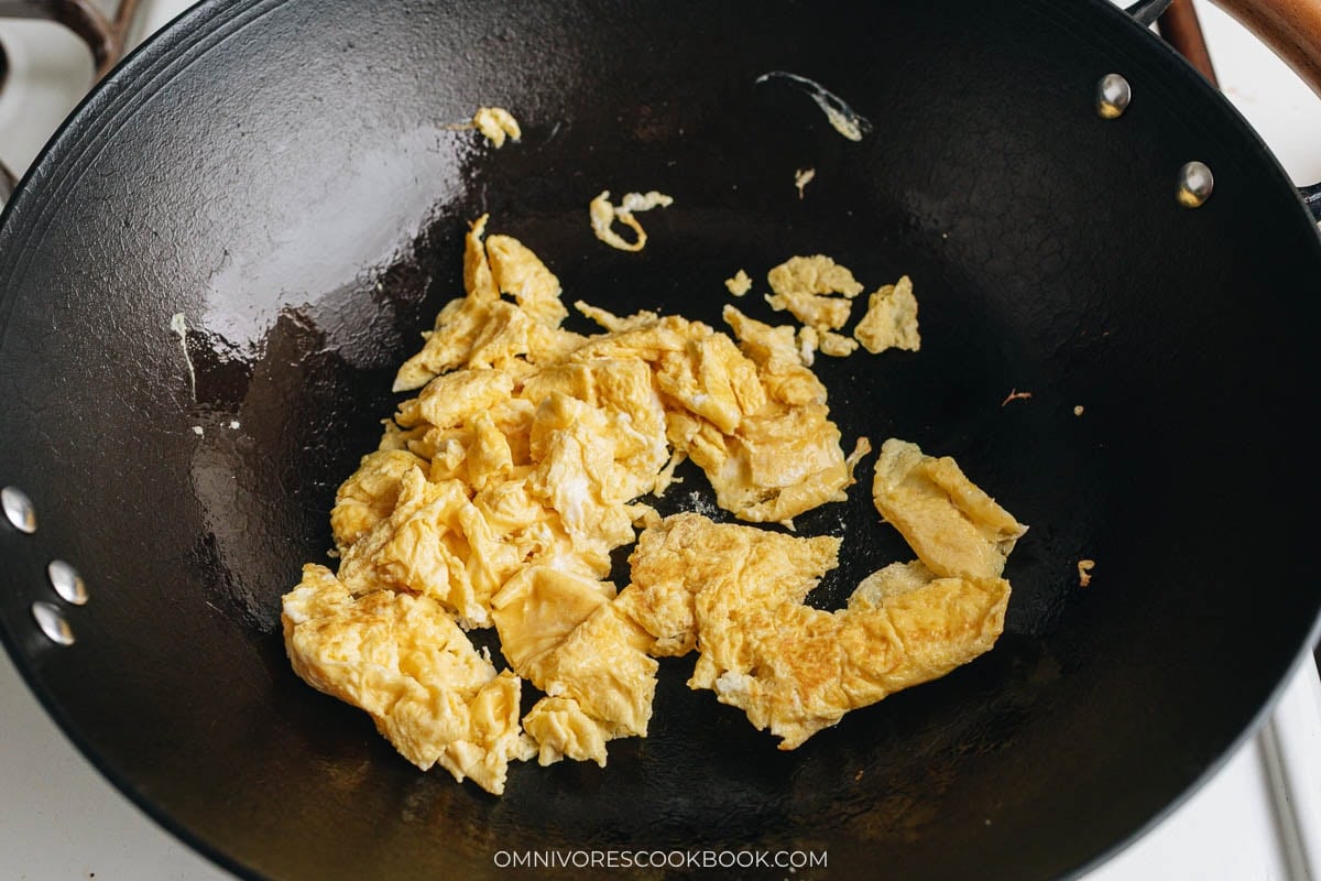 Scrambled eggs cooking in a hot wok as the first step.