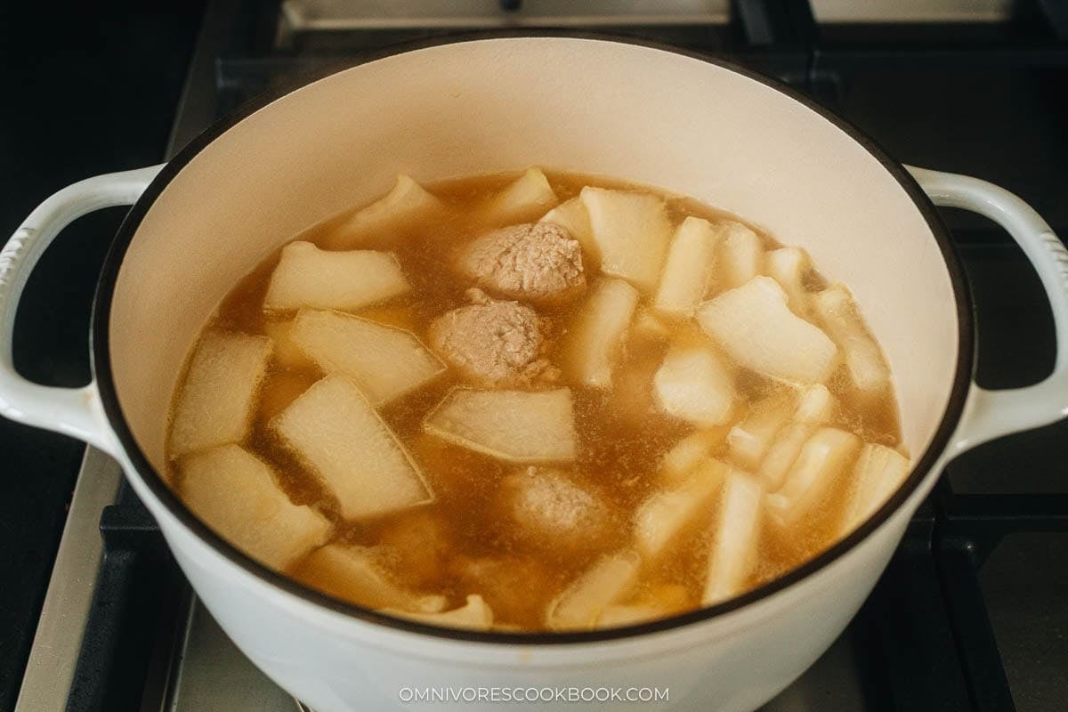meatballs and chunks of winter melon simmer in a pot of broth