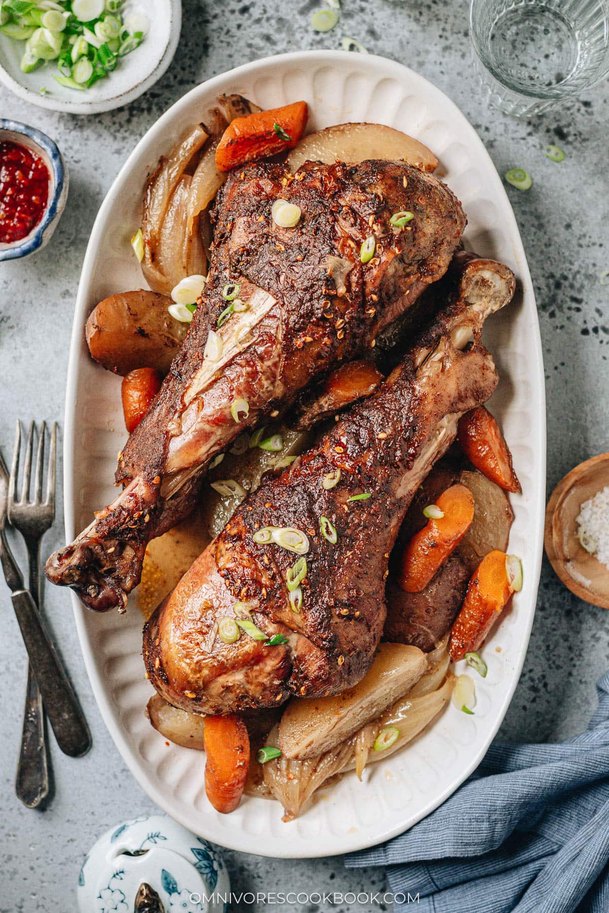 Roast turkey legs over a bed of vegetable served in a platter