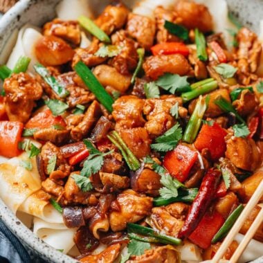 Close-up of Big Plate Chicken showing tender chicken pieces, soft potatoes, red peppers, and scallions coated in rich spicy sauce.