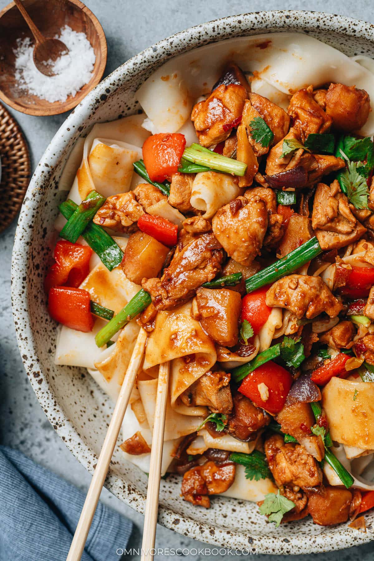 Chopsticks lifting noodles and chicken pieces, showing the thick sauce coating the ingredients of Da Pan Ji.