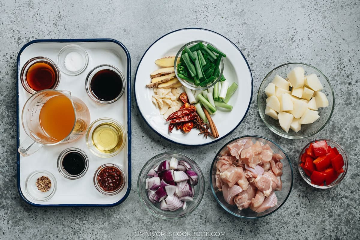 Ingredient prep photo showing seasonings, spices, aromatics, diced potatoes, chicken, and red peppers arranged in bowls for Da Pan Ji.