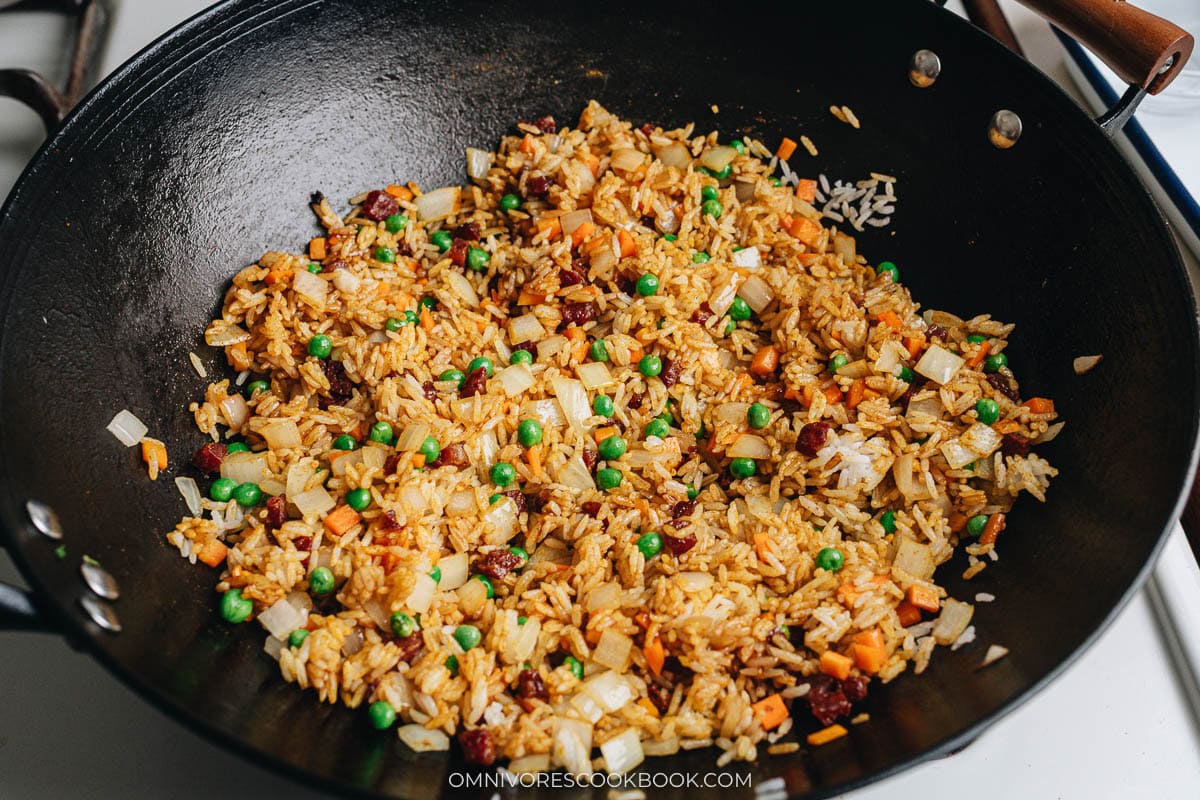 Rice stir-fried with vegetables and lap cheung, coated in curry sauce before shrimp and egg are added back in.
