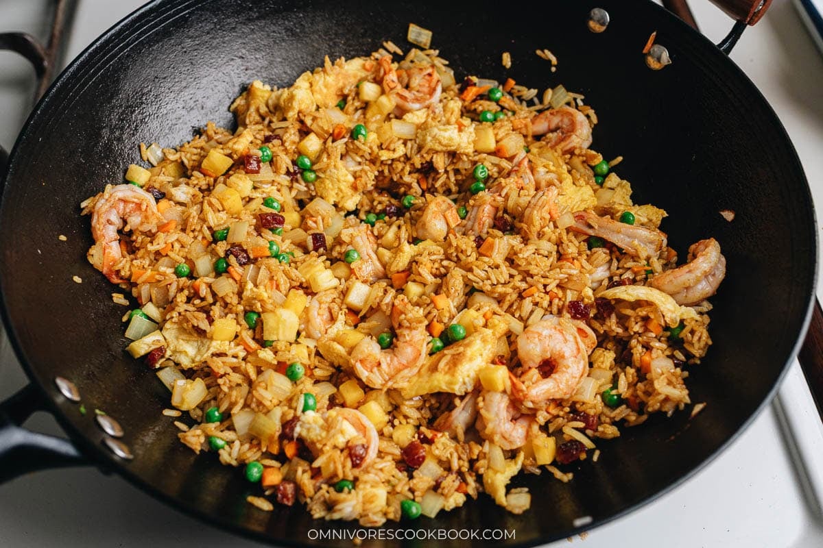 Finish up cooking Thai pineapple fried rice in a wok by adding back shrimp and egg.