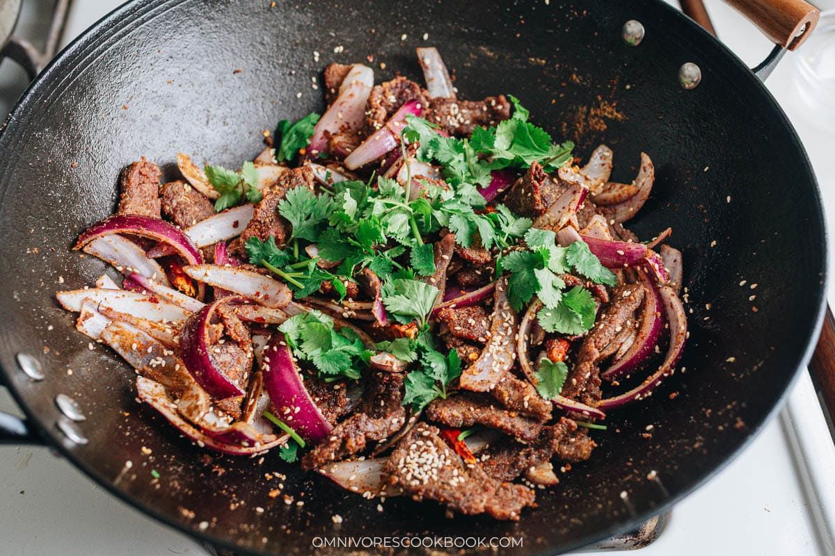 Adding cilantro to the stir fry to finish cooking the dish.